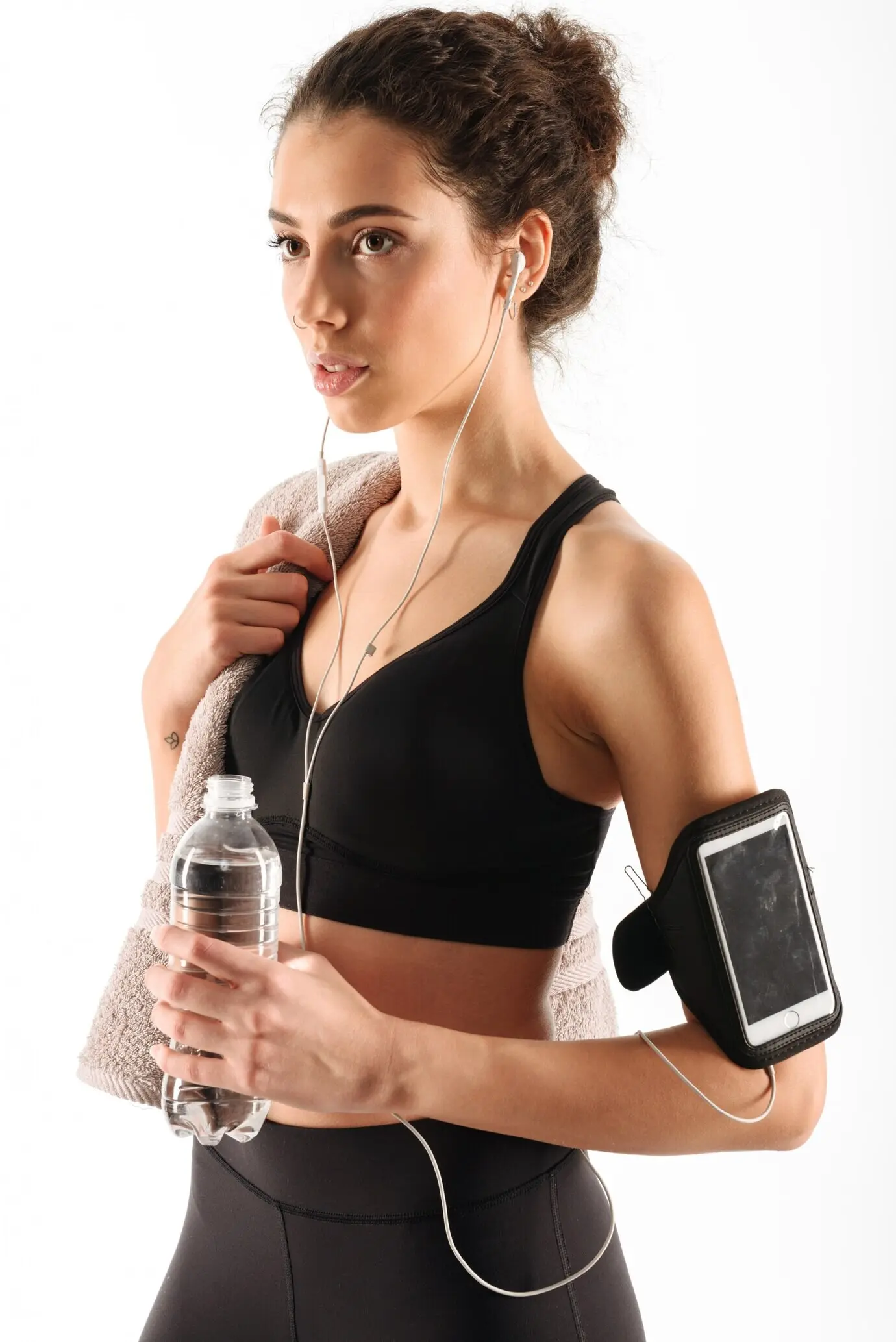 Hübsche, lockige, brünette Fitnessfrau mit einer Flasche